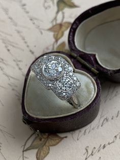 A trio of scintillating old European cut diamonds, together weighing 2.65 carats, flash across the face of this streamlined Edwardian / Art Deco finger hugger. Expertly crafted in platinum, three sparkling diamonds radiate from within a twinkling border of rose cut and old mine cut diamonds. Stunning from all angles. Currently a ring size 6 3/4. Center diamond: 1 ct., G color, VVS2 clarity Side diamonds: approximately .45 ct each, H-I color, one diamond is SI1 clarity, the other VS1 Diamond bord Art Deco Three Stone Diamond Ring, Three Stone Platinum Diamond Ring, Platinum Three Stone Diamond Ring For Anniversary, Cluster Three Stone Diamond Ring For Anniversary, Three Stone Cluster Diamond Ring For Anniversary, Platinum Three-stone Baguette Cut Diamond Ring, Platinum Three Stone Diamond Ring With Baguette Cut, Three Stone Baguette Cut Platinum Diamond Ring, Diamond Trilogy Ring