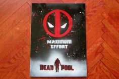 a deadpool movie poster sitting on top of a wooden floor