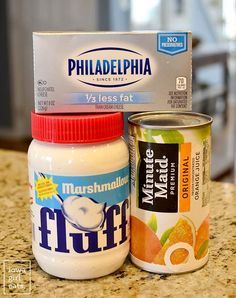 two jars of yogurt and a carton of oranges on a counter