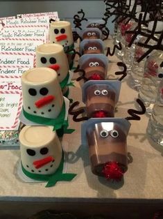 the table is set up with cups decorated like snowmen and reindeer noses for christmas