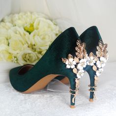 a pair of green high heeled shoes with flowers on the side, next to a bouquet of white roses