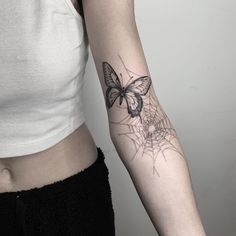 a woman's arm with a butterfly and spider web tattoo on the left forearm