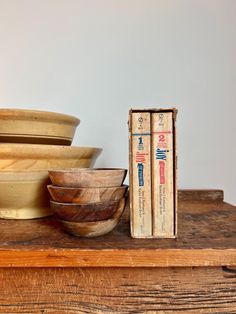 a stack of bowls sitting on top of a wooden table next to a book and some books