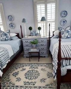 two beds in a bedroom with blue and white decor on the walls, along with a rug