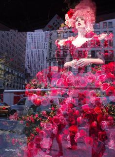 a window display with red roses in the shape of a woman's head and hands