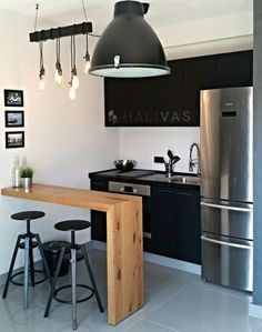 a kitchen with black cabinets and stainless steel appliances is pictured in this image, there are three stools at the counter