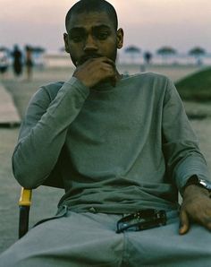 a man sitting in a chair with his hand on his chin and looking at the camera