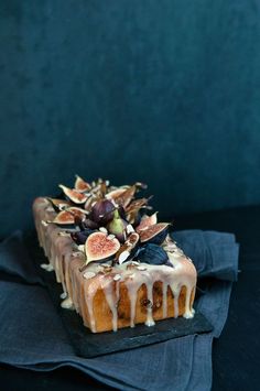 a cake that is sitting on top of a cloth with icing and figs