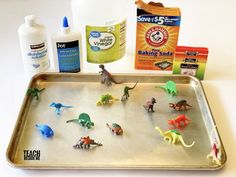 various toy dinosaurs on a baking pan with baking soda