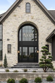 a stone house with black double doors and glass windows on the front door is shown