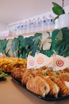 an assortment of food on a plate with flags in the middle and green leaves behind it