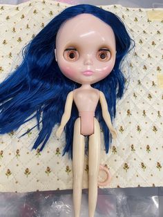 a doll with blue hair laying on a bed