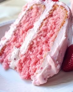 a piece of pink cake with white frosting and strawberries