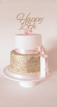 a white and gold wedding cake with pink flowers on top