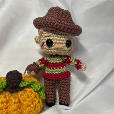 a small crocheted doll next to a pumpkin