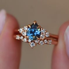 a person holding a ring with a blue stone in it's center and diamonds around the band