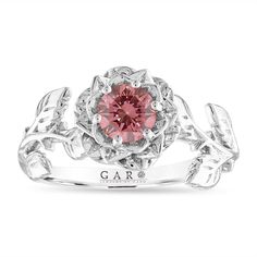 a white gold ring with a pink stone in the center and leaves on it's sides