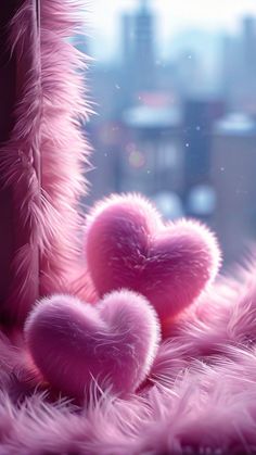 two fluffy pink hearts sitting next to each other on top of a window sill