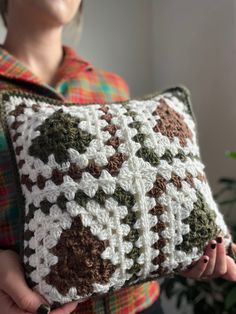 a woman holding a crocheted pillow in her hands