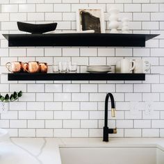 black and white kitchen with open shelving above the sink