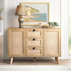 a sideboard with two drawers and a lamp on top of it next to a painting