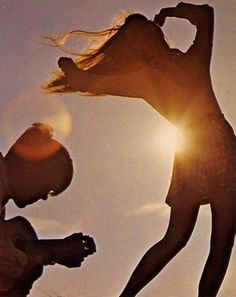 two people standing in front of the sun with their hands up and one person holding his head