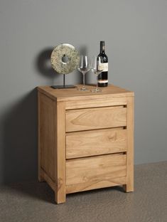 a bottle of wine and two glasses sit on a wooden cabinet next to a corkscrew sculpture