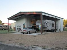 a car is parked in front of a metal building with a trailer attached to it