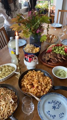 a table full of food and wine glasses on the dining room table with candles in the middle