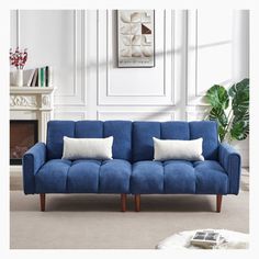 a blue couch sitting in front of a fireplace with two pillows on top of it