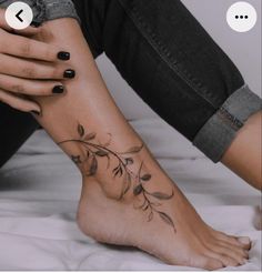 a woman's foot with flowers on it and an arrow in the middle of her left leg