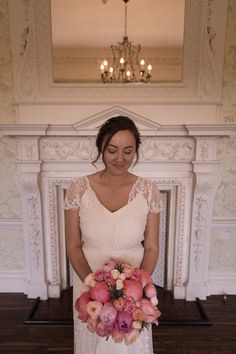 a woman standing in front of a fire place holding a bouquet of flowers