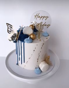 a white cake with blue and gold decorations on it's side, sitting on a plate