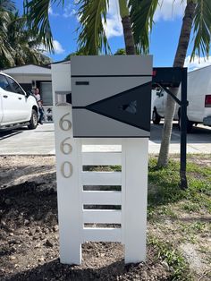 a white mailbox sitting on the side of a road next to a palm tree