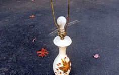 a white and gold vase sitting on top of a parking lot next to a lamp