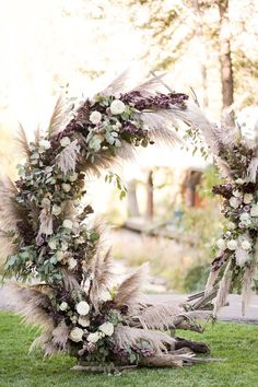 an outdoor wedding arch decorated with flowers and feathers