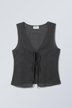 A slim fit vest top crafted from a crisp plain cotton. It has a V-neckline, a double tie front closure, darts at the bust and in the back for added structure and falls at the hips. Cool Pieces Of Clothing, Diy Vest Top, Vest Top Sewing Pattern, Cute Spring Tops, Grey Top Outfit, Vest Top Outfits, Tie Front Vest, Clothes Pieces, Black Vest Top