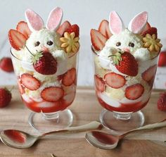 two glasses filled with strawberries and decorated like rabbits on top of a wooden board