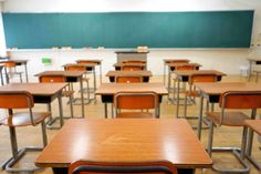 an empty classroom filled with wooden desks and chairs