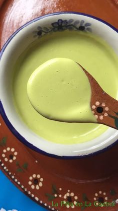 a spoon in a bowl filled with green liquid on top of a blue and brown plate