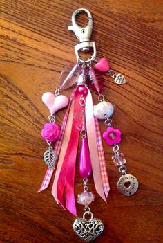 a key chain with charms and hearts on it sitting on a wooden table next to a bottle opener