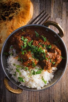 a bowl filled with rice and meatballs on top of a wooden table next to bread