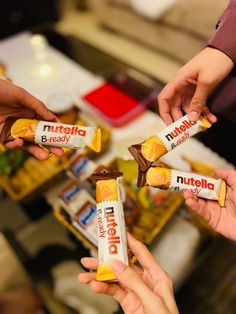 three people holding up nutella bars in their hands