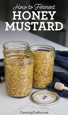 two jars filled with honey mustard sitting on top of a table