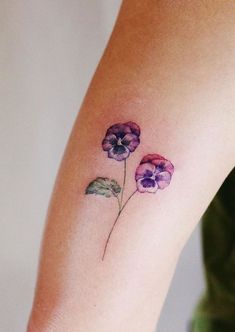 a woman's arm with three small flowers on the left side of her body