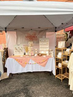 an outdoor market tent set up with items for sale on the table and in front of it