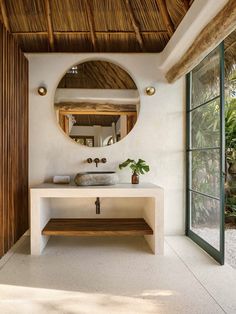 a bathroom with a sink and mirror next to a wooden bench in front of a window