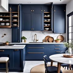 a kitchen with blue cabinets and marble counter tops, gold pulls on the cupboards