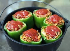 green peppers stuffed with meat and sauce in a black pot on a counter top, ready to be eaten