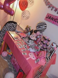 a pink table topped with zebra print and balloons